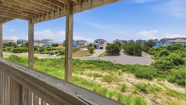 A wooden deck overlooking a residential area with houses and greenery. - The Final View | 750 ft to the beach | Private Pool, Hot Tub, and Dog Friendly (Corolla)