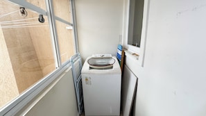 Quarto compacto com máquina de lavar, janela e porta.