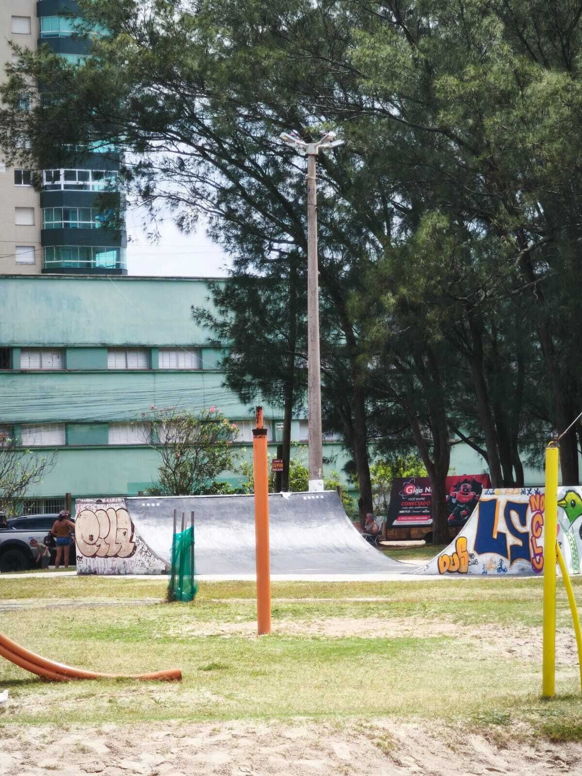 A skate park with ramps and graffiti, surrounded by trees and buildings.