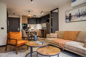 A modern living room with a sofa, armchair, coffee table, and a dining area with a table and chairs. - Modern 2BR Providencia Oasis with Pool and Gym (Santiago)