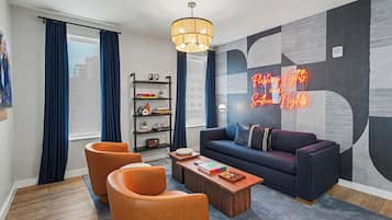 A modern living room with a sofa, two armchairs, a coffee table, a bookshelf, and a neon sign.