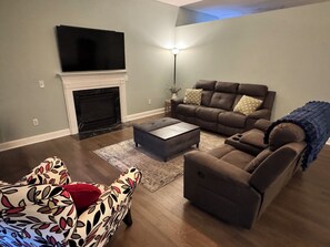 A living room with a fireplace, a sofa, a loveseat, and a television.