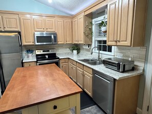 A modern kitchen with wooden cabinets, stainless steel appliances, and a granite countertop. - Cozy Getaway - Pet-Friendly + Screened Porch (Concord)
