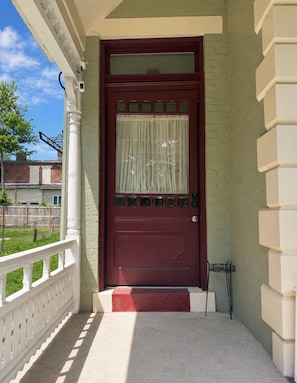 Eine rote Tür mit Fensterteil und einem weißen Zaun.