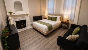 A hotel room with a bed, a sofa, a fireplace, a desk, and a mirror. - A Grand Historic Retreat-Downtown Covington-Sleeps 3 (Covington)