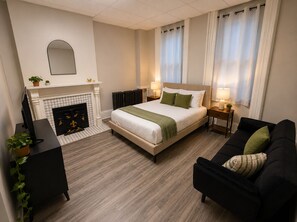 Ein Hotelzimmer mit einem Bett, einer Couch, einem Kamin, einem Schreibtisch und einem Spiegel.