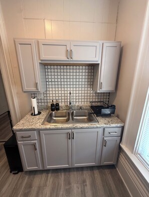 A compact kitchen with two sinks, a countertop with a paper towel holder, and a backsplash with hexagonal tiles. - A Grand Historic Retreat-Downtown Covington-Sleeps 3 (Covington)