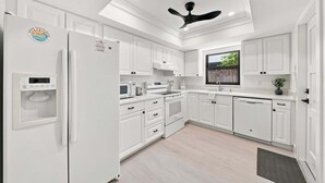 A modern kitchen with white cabinetry, a built-in oven, a microwave, and a refrigerator. - New! Blue Haven - Heated Saltwater Pool/Spa, 1 Mile to the Beach! (Naples)