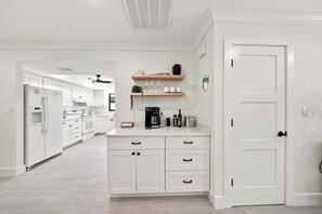 A modern kitchen with white cabinetry, a built-in oven, and a coffee station. - New! Blue Haven - Heated Saltwater Pool/Spa, 1 Mile to the Beach! (Naples)