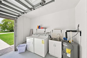 A laundry facility with two washing machines, a sink, and a water heater. - New! Blue Haven - Heated Saltwater Pool/Spa, 1 Mile to the Beach! (Naples)