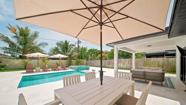 A backyard with a pool, outdoor furniture, and a covered patio area. - New! Blue Haven - Heated Saltwater Pool/Spa, 1 Mile to the Beach! (Naples)
