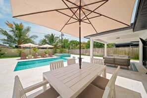 A backyard with a pool, outdoor furniture, and a covered patio area. - New! Blue Haven - Heated Saltwater Pool/Spa, 1 Mile to the Beach! (Naples)