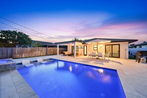A modern house with a swimming pool, outdoor seating, and a patio area. - New! Blue Haven - Heated Saltwater Pool/Spa, 1 Mile to the Beach! (Naples)