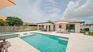A backyard with a swimming pool, patio furniture, and a barbecue grill. - New! Blue Haven - Heated Saltwater Pool/Spa, 1 Mile to the Beach! (Naples)