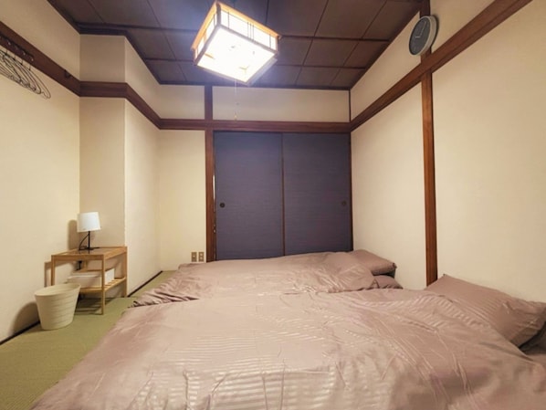 Una habitación con cama, mesita de noche, lámpara y armario.