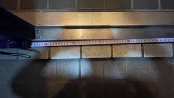 A measuring tape across a tiled floor, indicating the room's dimensions.