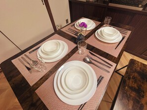 A dining table set with white plates, cutlery, and a glass of water.