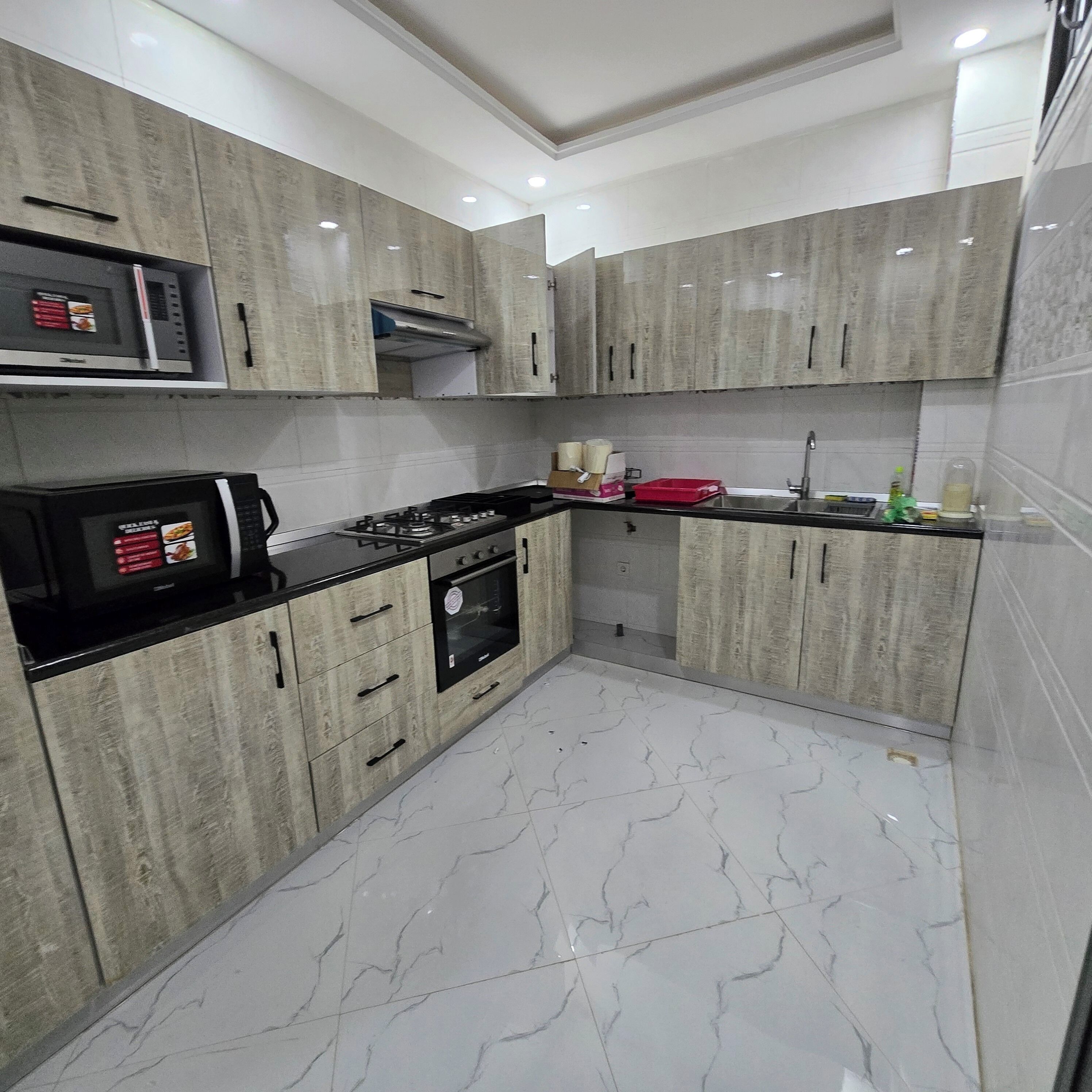 Una cocina moderna con armarios grises, encimera negra, microondas integrado y estufa.