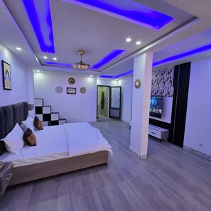 A modern bedroom with a bed, a TV, and a ceiling fan.
