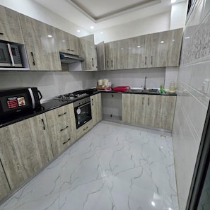 Una cocina moderna con gabinetes grises, una encimera negra, un microondas, una estufa y un lavamanos.