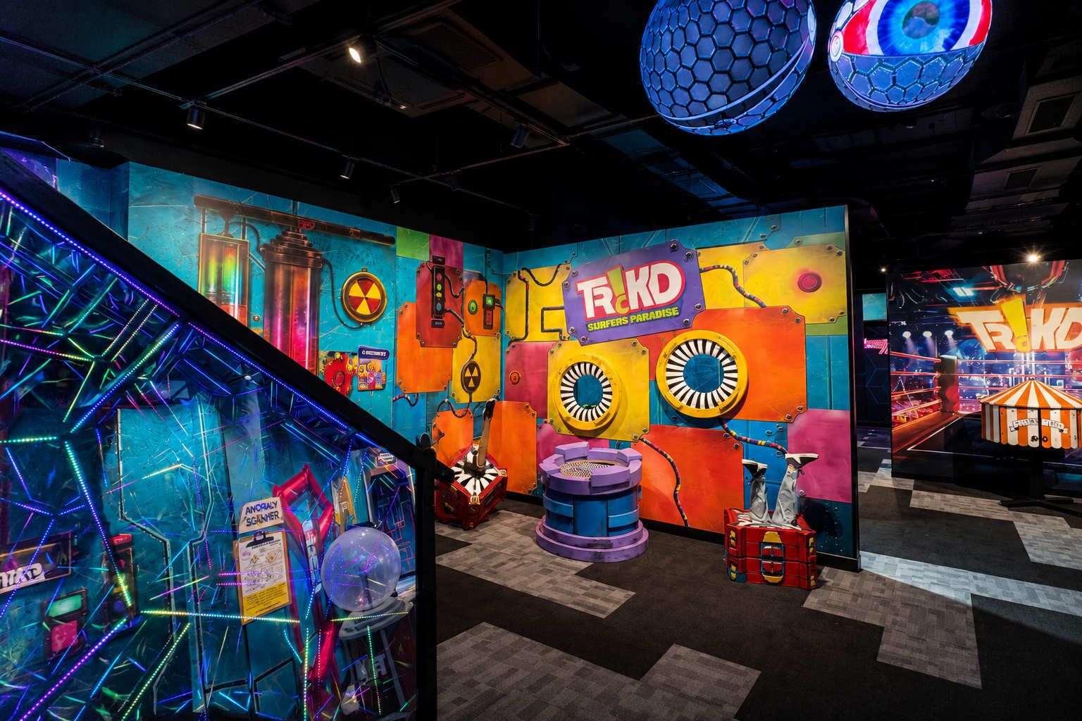 A colorful room with a large mural, a spherical object, and a sign that reads 'TRKD SURFERS PARADISE'.