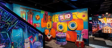 Una habitación colorida con un gran mural, un objeto esférico y un cartel que dice 'TRKD SURFERS PARADISE'.