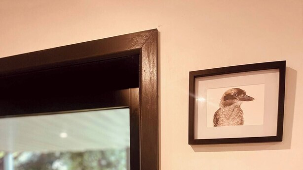 Un cuadro enmarcado con un pájaro y un sombrero en la pared.