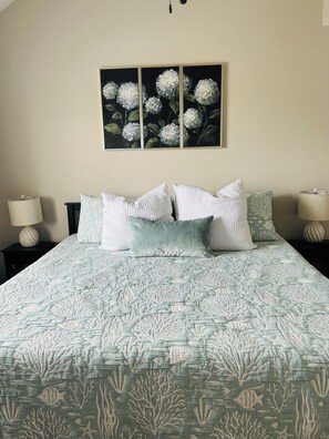 A bedroom with a bed, pillows, a nightstand, a lamp, and a wall-mounted painting. - Surfside Beach Retreat , Pool, Hot Tub, Pickleball & Minutes to the Beach (Surfside Beach)