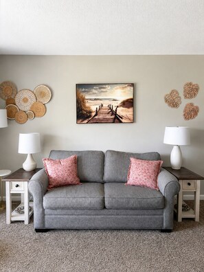 A living room with a grey sofa, two lamps, a wall-mounted picture, and decorative wall art. - Surfside Beach Retreat , Pool, Hot Tub, Pickleball & Minutes to the Beach (Surfside Beach)