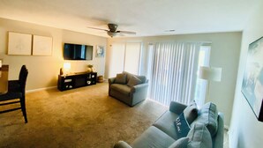 A living room with a ceiling fan, a flat-screen TV, a sofa, a chair, and a coffee table.