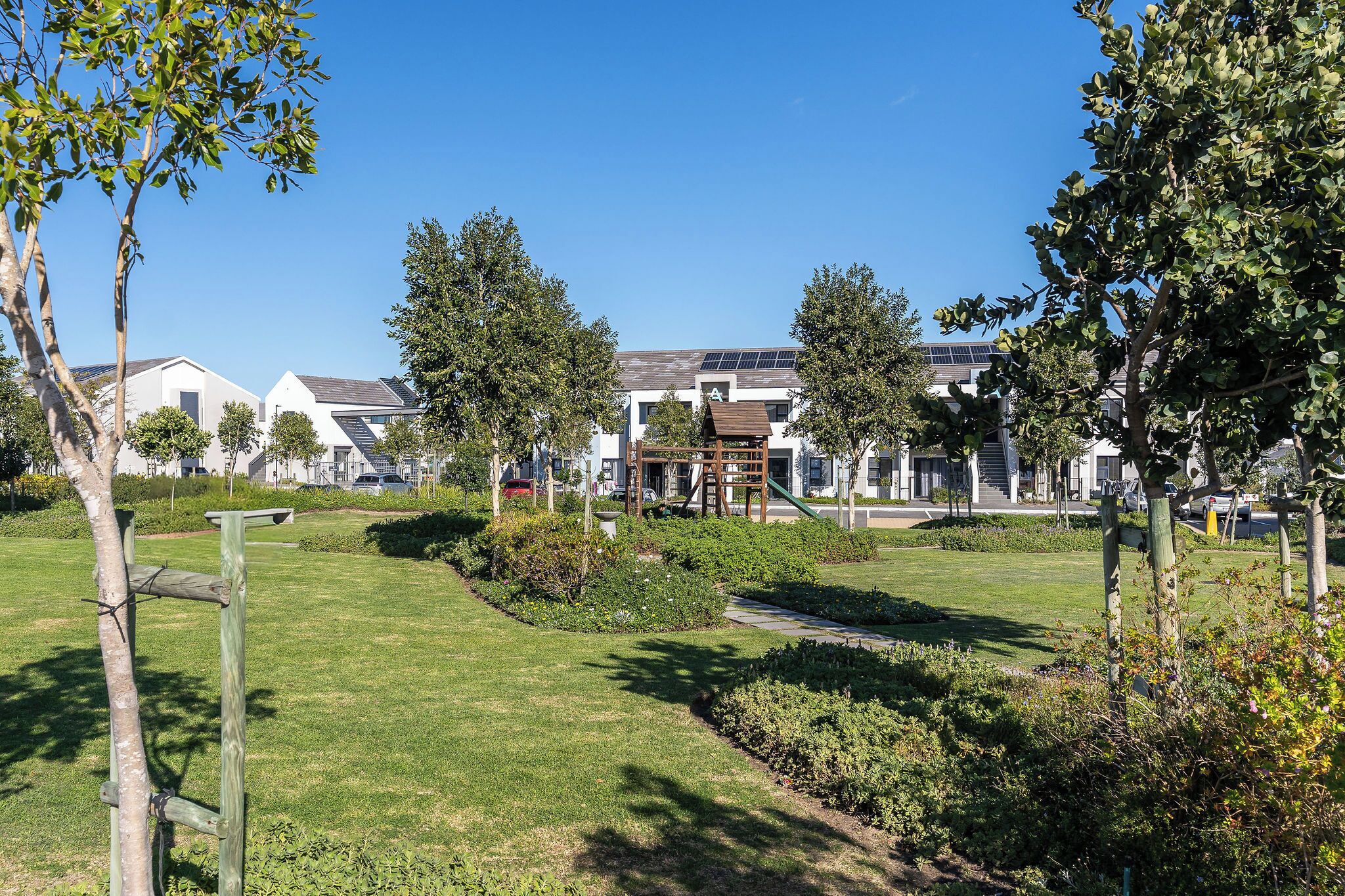 A residential area with modern houses, a playground, and a well-maintained lawn.