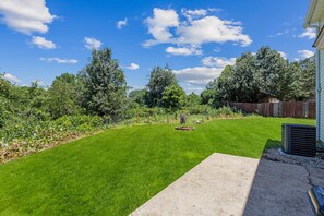 A well-maintained backyard with a lawn, a wooden deck, and a fence. - 5BR/3BA Retreat | Near Stone Mountain | Sleeps 10 (DeKalb County)