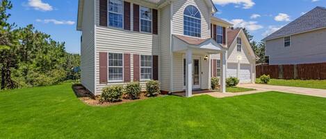 A two-story house with a front porch, a garage, and a well-maintained lawn.