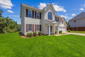 A two-story house with a front porch, a garage, and a well-maintained lawn. - 5BR/3BA Retreat | Near Stone Mountain | Sleeps 10 (DeKalb County)