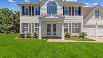 A two-story house with a front porch, a garage, and a well-maintained lawn.