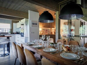 Comedor con una mesa de madera dispuesta para una comida, rodeada de sillas y una lámpara colgante grande.