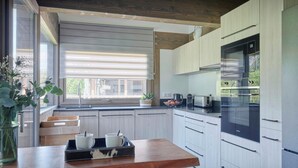 Une cuisine moderne avec des meubles en bois, un four encastré et une fenêtre donnant sur un paysage verdoyant.