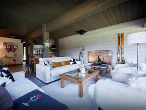 A cozy living room with a white sofa, a wooden coffee table, and a television displaying a Paramount logo. - Alpaga Cosima - Peaceful chalet for every season - OVO Network (Châtel)