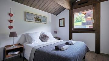 A bedroom with a bed, two bedside tables, a window, and a painting on the wall.