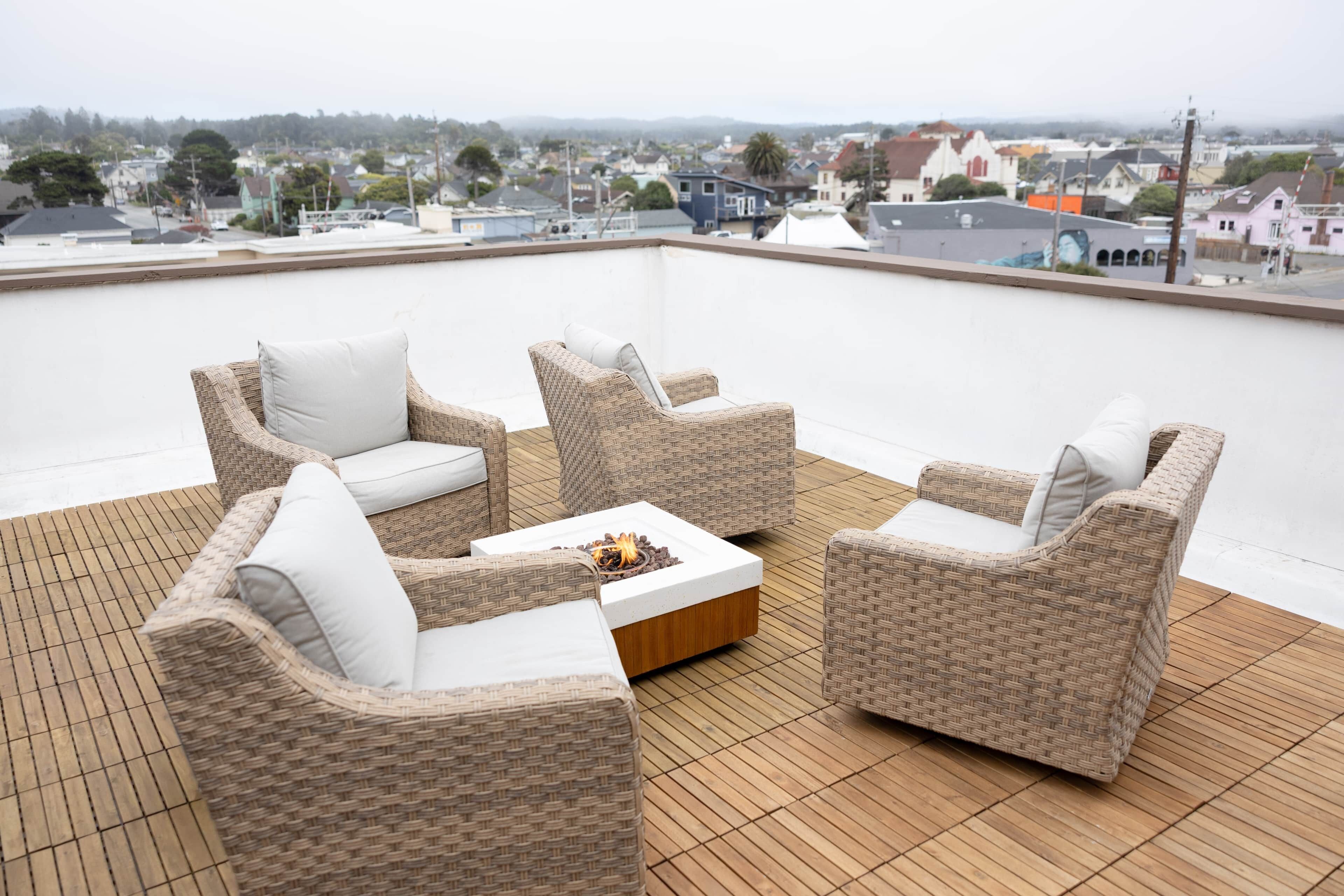 Une terrasse sur le toit, aménagée avec des meubles en osier et un foyer.