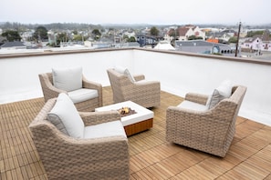 Une terrasse sur le toit, aménagée avec des meubles en osier et un foyer.