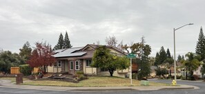 Une maison d’habitation dotée de panneaux solaires, d’une pelouse devant et d’un panneau de signalisation.
