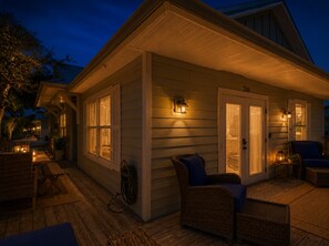 Une maison en bois avec un porche, des meubles en osier et le numéro 216 sur la porte.