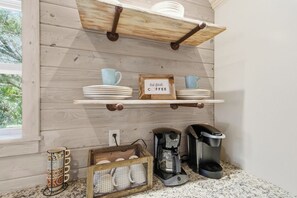 A kitchen with wooden walls, a coffee station with a Keurig machine, and a sign that says 'but first, COFFEE'. - 1 Block to Beach | New Outdoor Living Space (St Augustine)
