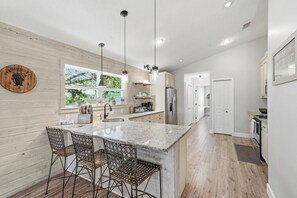A modern kitchen with a large island, pendant lighting, and a view of the outdoors. - 1 Block to Beach | New Outdoor Living Space (St Augustine)