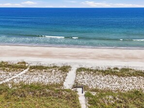A beach with a sandy path leading to a wooden structure, overlooking a calm sea. - 1 Block to Beach | New Outdoor Living Space (St Augustine)