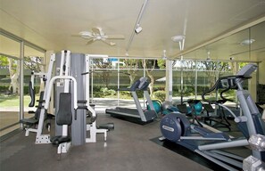 A gym with cardio machines, weightlifting equipment, and a glass wall offering a view of the outdoors. - Perfect Ocean view 2-bedroom condo that’s centrally located near Ala Moana beach (Honolulu)