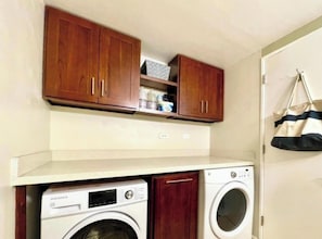 A laundry area with wooden cabinets, a washing machine, and a drying machine.
