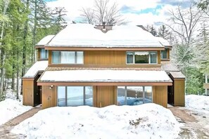 A two-story house with a snow-covered roof and a large glass front. - Mountainside Retreat @ Attitash, Ski-In, Ski-Out, Pool, Hiking (Bartlett)
