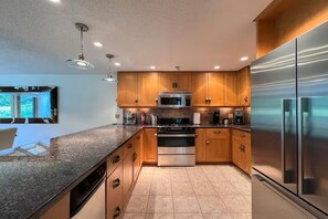 A modern kitchen with wooden cabinets, stainless steel appliances, and a granite countertop. - Mountainside Retreat @ Attitash, Ski-In, Ski-Out, Pool, Hiking (Bartlett)